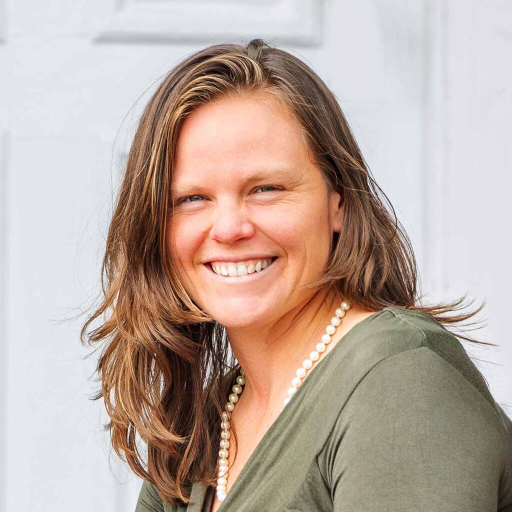 Smiling woman with long hair and necklace.