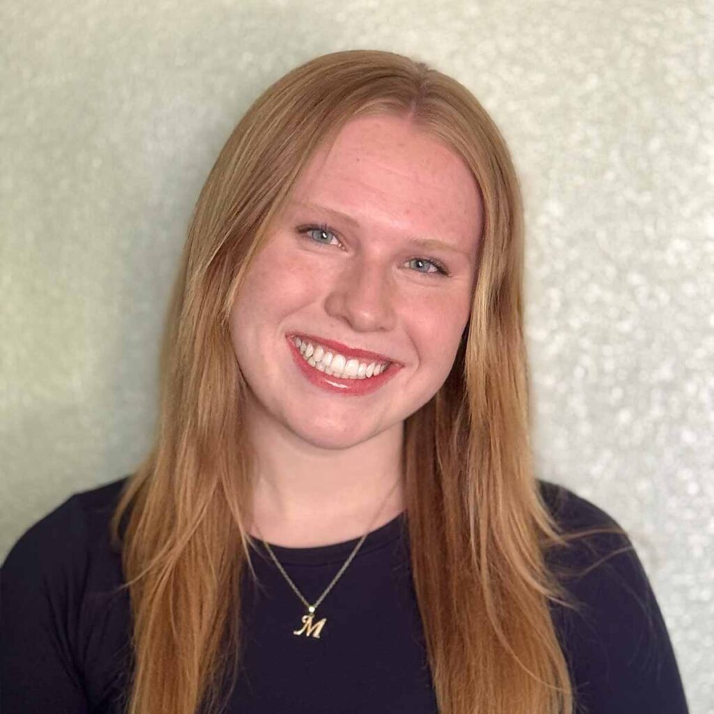 Smiling person with long hair against a textured background.
