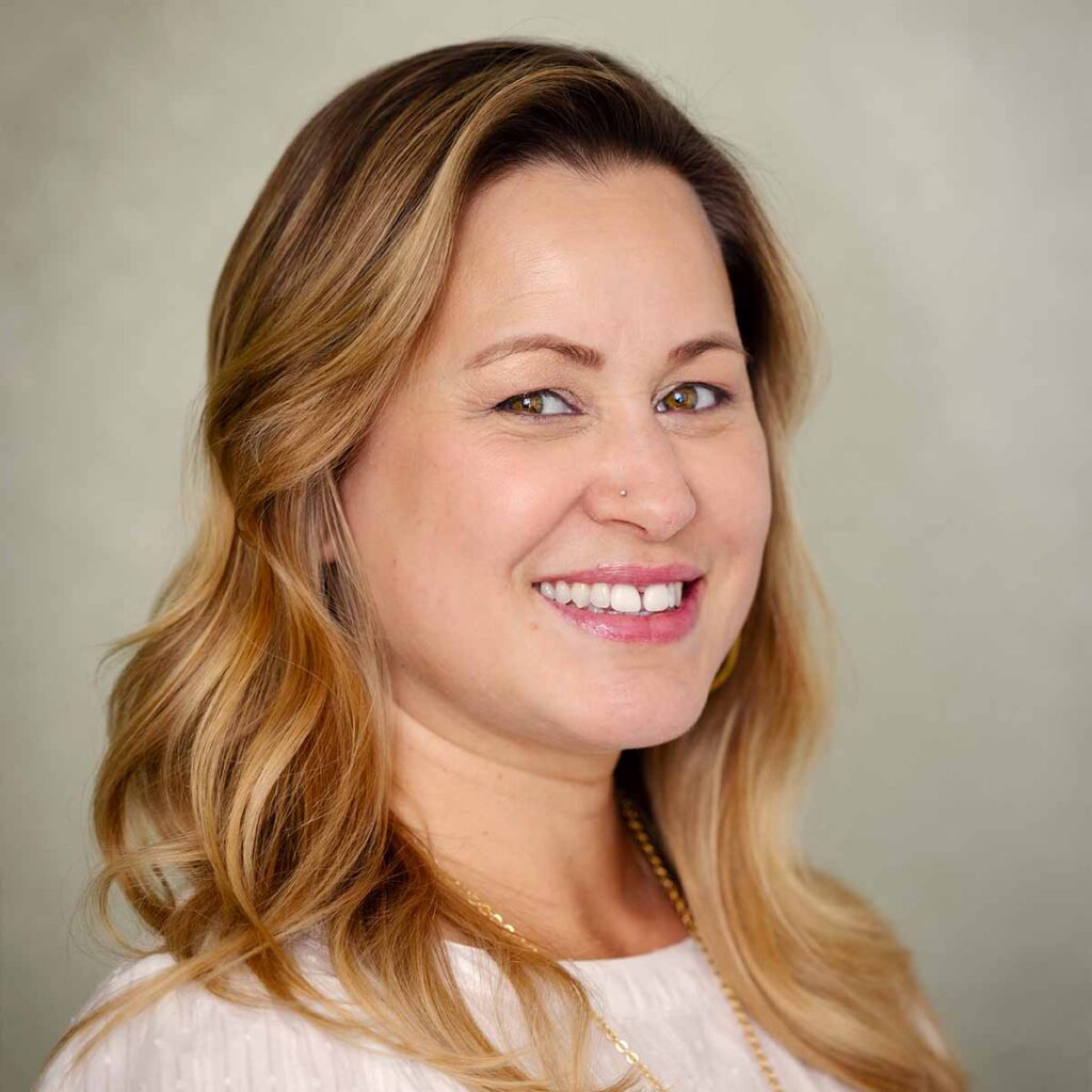 Smiling woman with long blonde hair and earrings.